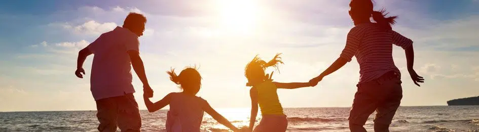 A family holding hands in the sunset at a Waterside Holiday Group resort.
