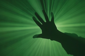 Silhouette of a hand in front of a green background