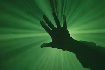 Silhouette of a hand in front of a green background